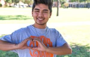 A student making a heart shape with his h和s to thank donors.